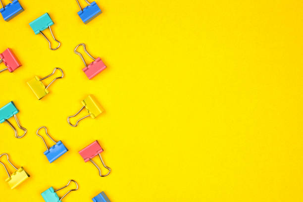 istock Pasted paper clip side border on a bright yellow background with copy space 1159643722
