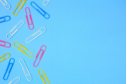 Paper clip side border. Top view on a blue paper background with copy space.