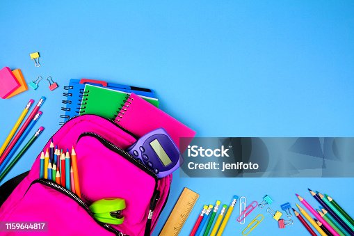istock Pink backpack with corner border of school supplies against a blue paper background with copy space 1159644817