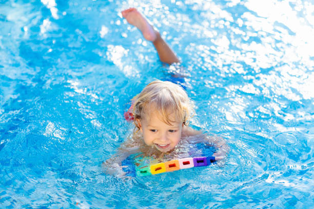 istock Child learning to swim. Kids in swimming pool. 1159646855