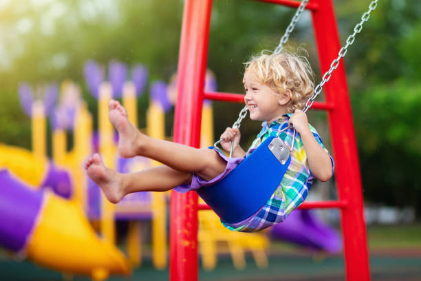 niño en el patio de recreo. swing niños juegan al aire libre. - child swing swinging spring fotografías e imágenes de stock