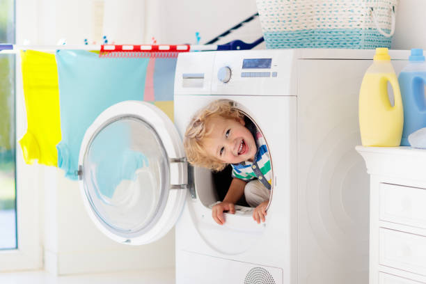 Child in laundry room with washing machine Child in laundry room with washing machine or tumble dryer. Kid helping with family chores. Modern household devices and washing detergent in white sunny home. Clean washed clothes on drying rack. tumble dryer stock pictures, royalty-free photos & images