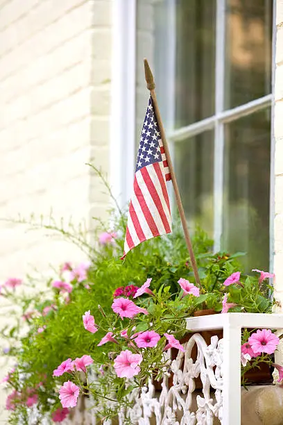 A window box with pink petunias and the American flag.