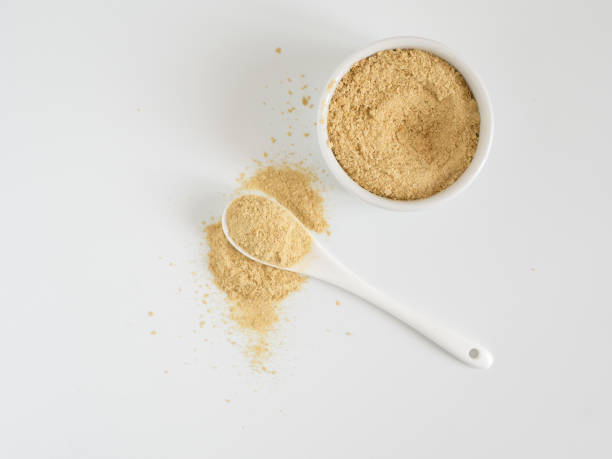 Nutritional inactive yeast top view Nutritional yeast. Nutritional inactive yeast in small white ctramic bowl and white ceramic spoon. Copy space. Top view. Nutritional yeast is vegetarian superfood with cheese flavor, for healthy diet yeast stock pictures, royalty-free photos & images