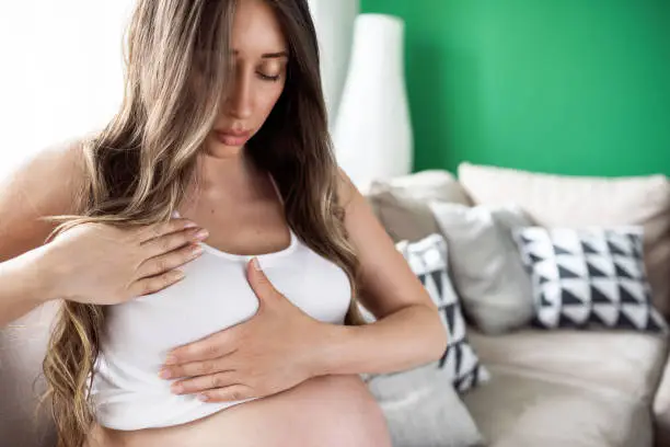 Closeup of pregnant woman having painful feelings in breast