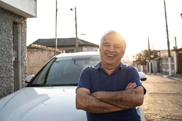 porträt eines lächelnden seniors vor einem auto und blick in die kamera - taxifahrer stock-fotos und bilder