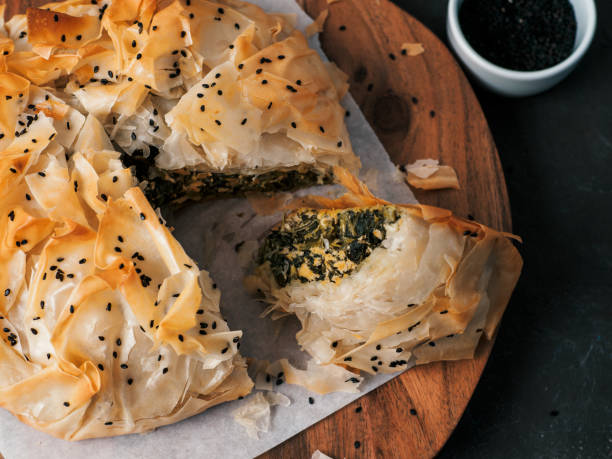 Vegan Spanakopita Spinach Pie Greek pie spanakopita on dark background. Ideas and recipes for vegetarian or vegan Spanakopita Spinach Pie from fillo pastry cut in slices. Copy space. Top view or flat lay. spanakopita stock pictures, royalty-free photos & images