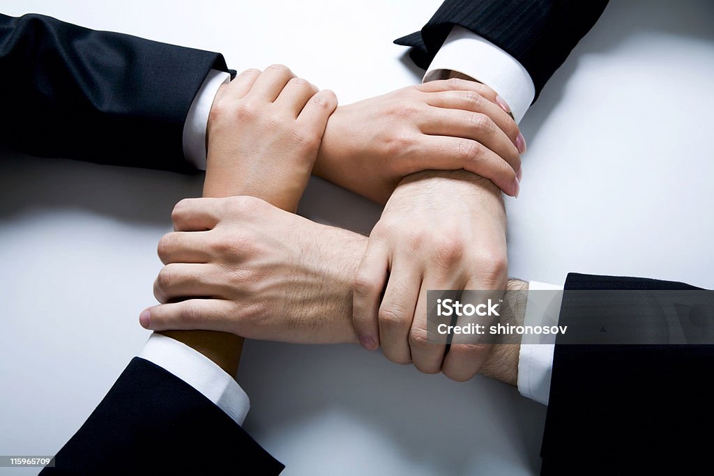 Four hands joined together in harmony Isolated on white four crossed human hands in business wear Adult Stock Photo