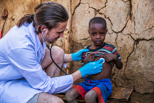 Médico que examina a un joven africano en un pequeño pueblo, Kenia photo