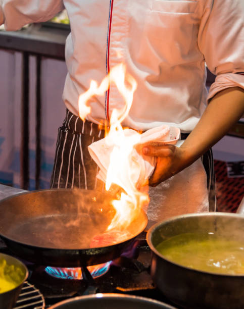 Chef cooking with flame in a frying pan on a kitchen stove