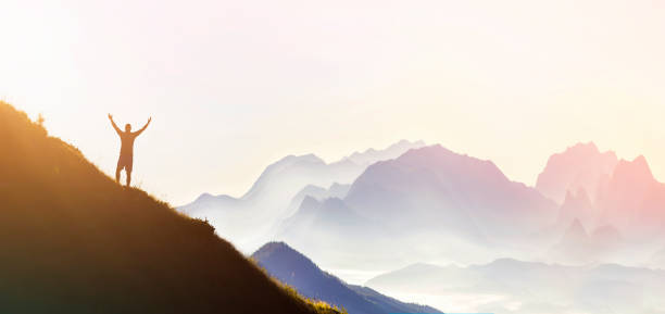 istock Man on peak of mountain. Emotional scene. Young man with backpack standing with raised hands on top of a mountain and enjoying mountain view. Hiker on the mountain top. Sport and active life concept. 1159660865