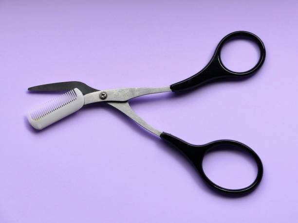 istock Eyebrow grooming scissors and comb on pink background 1159660998