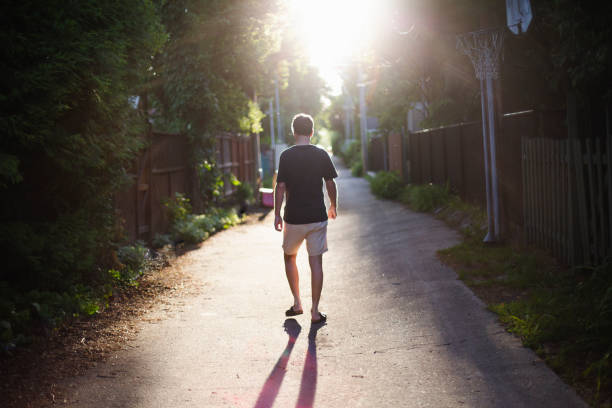 istock Man walking at sunset in an alley 1159661425