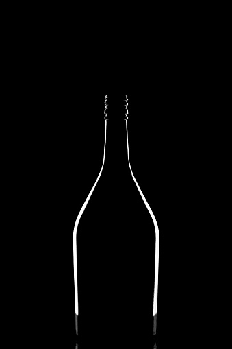 A stylish silhouette of elegant black corked wine bottle reflected and outlined by light on black background