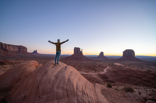 Rear view of man standing on rock at Monument Valley in USA. People travel America concept