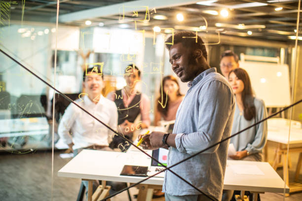 istock Black man writing on glass wall in the office 1159664226