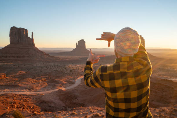Man on rock at Monument Valley in USA picture framing landscape with hands Man on rock at Monument Valley in USA framing sun rising on the horizon. People travel America concept hand cropping photos stock pictures, royalty-free photos & images