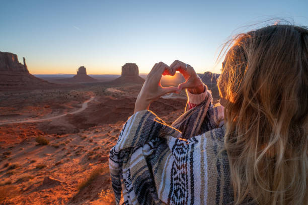 giovane donna nel deserto americano che fa telaio a forma di cuore con le mani amorevoli avventura di viaggio su strada - arizona desert landscape monument valley foto e immagini stock