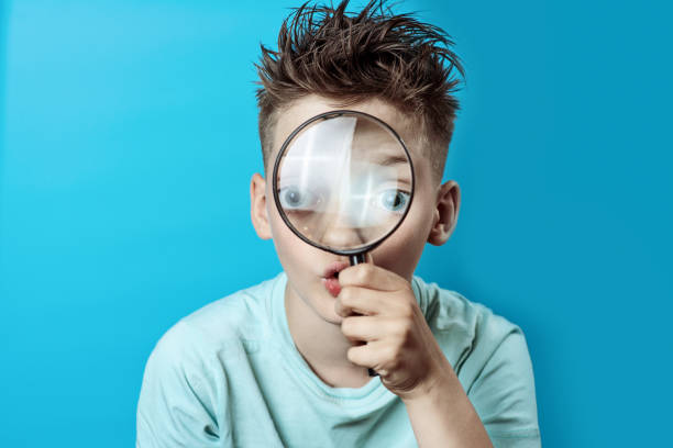 istock boy in a light t-shirt looking into a large magnifying glass 1159666001