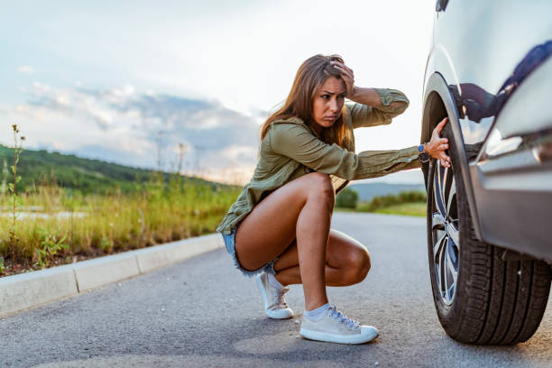 mujer con neumático plano de coche descompuesto - car stranded women breakdown fotografías e imágenes de stock