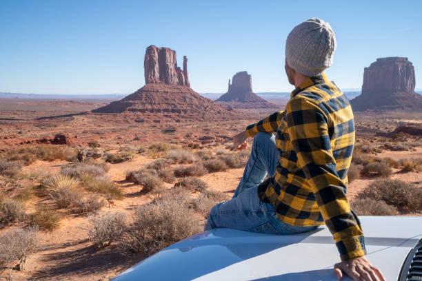 jeune homme avec la voiture de location appréciant le voyage de route aux etats-unis - navajo national monument photos et images de collection