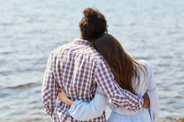 istock Young Couple Embracing by Lake 1159669291