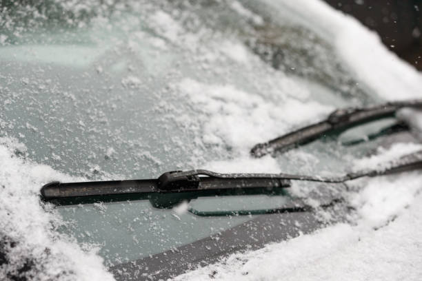 Car wiper blades clean snow from car windows. Flakes of snow covered the car with a thick layer. Safe driving with working wipers and clean windshield. Car wiper blades clean snow from car windows. Flakes of snow covered the car with a thick layer. Safe driving with working wipers and clean windshield. windshield wiper snow stock pictures, royalty-free photos & images