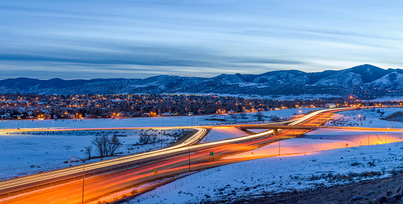 A panoramic overview of U.S. Highway 285 winding at the foothill of Front Range of Rocky Mountains on a stormy winter evening. Southwest of Denver, Colorado, USA.