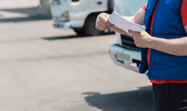 istock Courier driver in uniform making notes in document and delivery white truck behinde him 1159679310