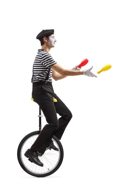 istock Mime juggler riding a unicycle and throwing plastic clubs 1159680689