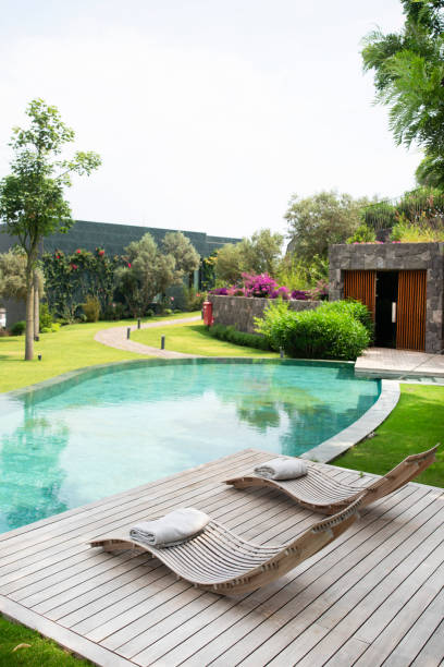istock Deck chairs on plank floor against swimming pool 1159680864