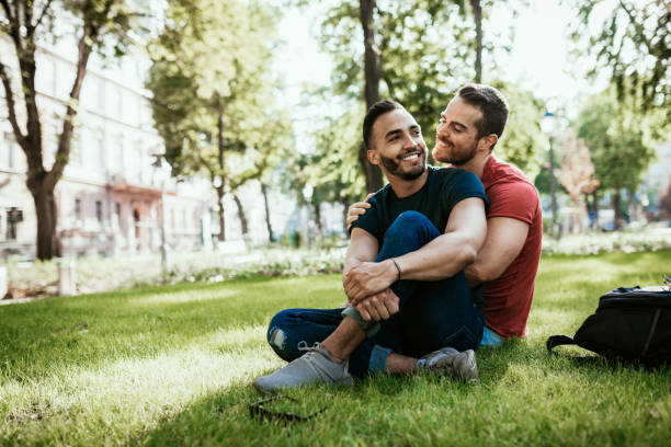 schwules paar - latino und europäische millennial männer - genießen im park im sommer - homosexuelles paar stock-fotos und bilder