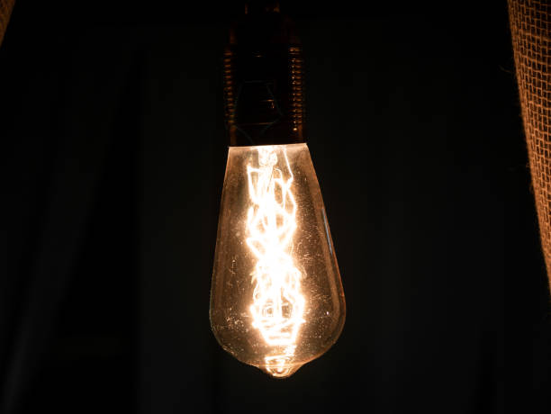 istock Single vintage light bulb in a dark room. 1159686441