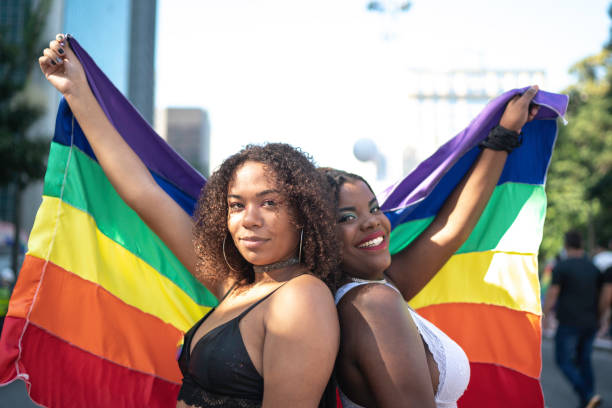 porträt von freunden, die während der pride parade regenbogenfahne schwenken - homosexual gay man parade flag stock-fotos und bilder