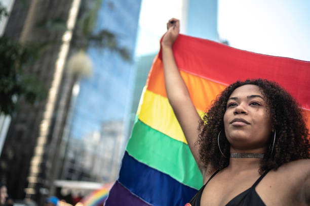 Woman waving rainbow flag during pride parade Woman waving rainbow flag during pride parade lgbtqia pride event photos stock pictures, royalty-free photos & images