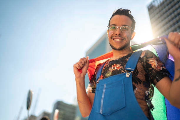 istock Young gay man holding rainbow flag and looking at camera 1159690476