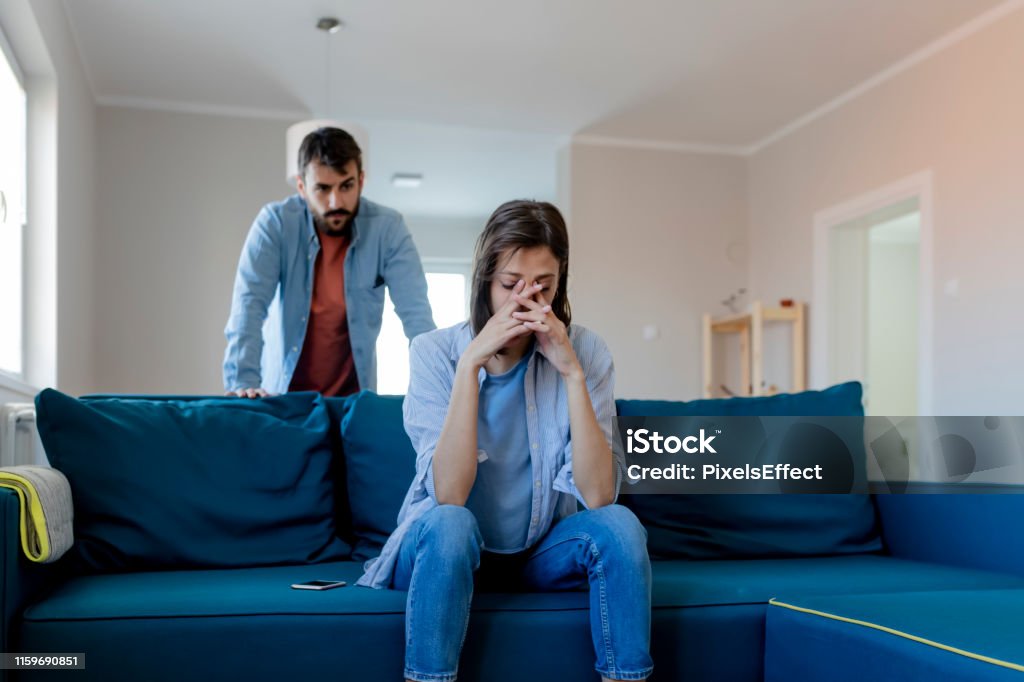 Angry Couple Having an Argument Angry Fury Man Screaming at Woman. Angry Couple Having an Argument in Their Living Room. Young Marriage Couple Have an Argument Because of Relationship Crisis. Couple Having Argument - Conflict, Bad Relationships. Couple - Relationship Stock Photo