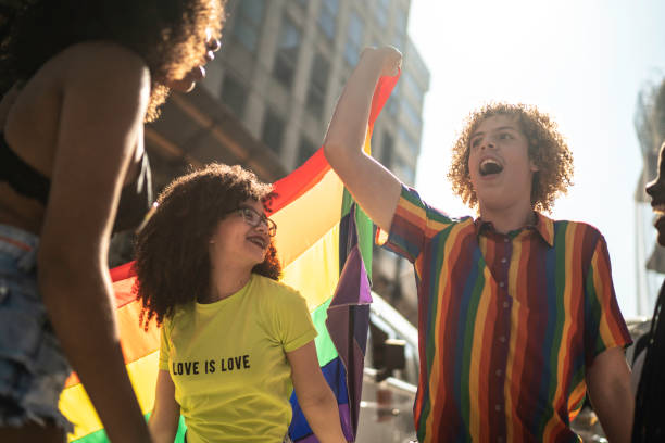 istock Happy friends holding rainbow flag during pride parade 1159692562