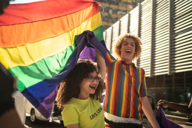istock Happy friends holding rainbow flag during pride parade 1159692590