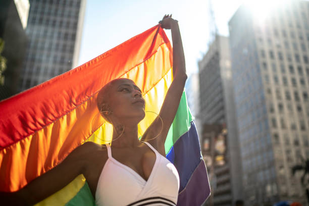 zuversichtliche lesbische frau hält regenbogen-flagge während stolz parade - homosexual gay man parade flag stock-fotos und bilder