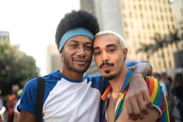 Male couple embracing during LGBTQI parade Male couple embracing during LGBTQI parade black men with blonde hair stock pictures, royalty-free photos & images