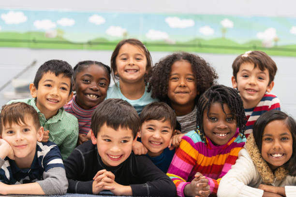 Close friends in class portrait A group of diverse kids smile in this portrait. They are stacked on top of each other while cuddling in close and showing how happy they are. elementary school building photos stock pictures, royalty-free photos & images