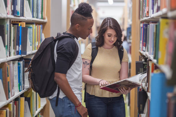 dwóch studentów rozmawiać w bibliotece - multi ethnic group couple sex women zdjęcia i obrazy z banku zdjęć