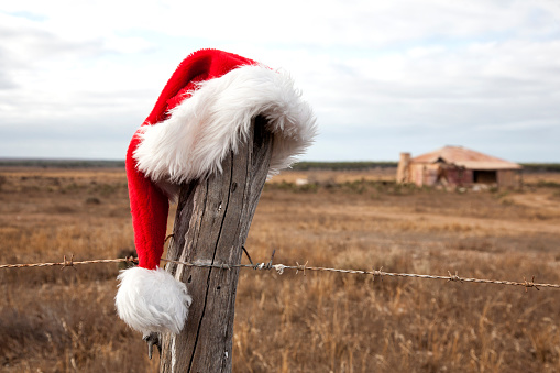Santa hat hanging on a rustic fence post, outback Australia