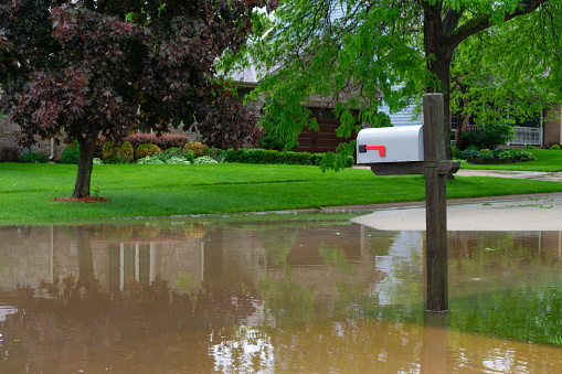 A suburban Midwestern neighborhood mailbox on a flooded street after a storm