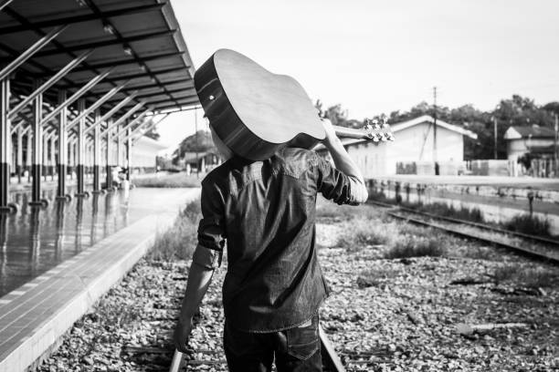 Guy with guitar on the railway road. Black and white photo