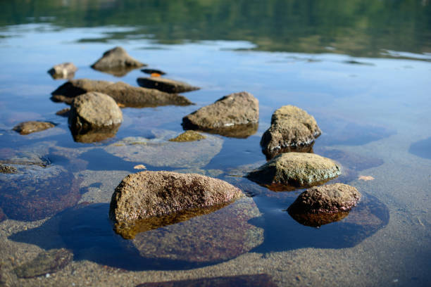 istock Wet pebbles on seashore in evening sun light. Sea wave on seacoast with round stones. 1159734526