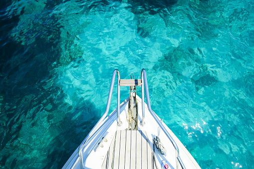 (Selective focus) Stunning view of a bow of a yacht sailing on a beautiful turquoise and transparent sea. Sardinia (Emerald Coast) Sardinia, Italy.