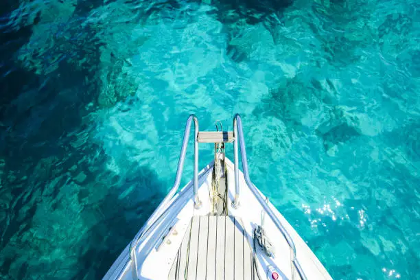 Photo of (Selective focus) Stunning view of a bow of a yacht sailing on a beautiful turquoise and transparent sea. Sardinia (Emerald Coast) Sardinia, Italy.