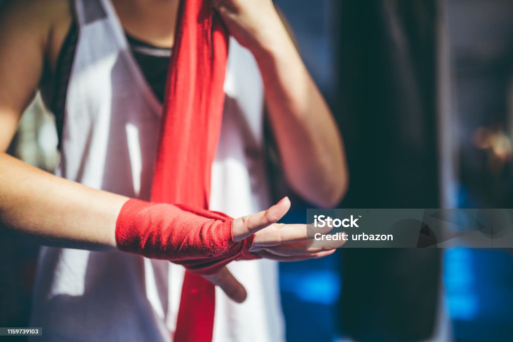 Tying up sports glove Young caucasian woman tying up sports glove and preparing for a training. Boxing - Sport Stock Photo